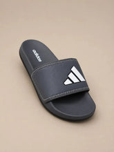 A single Adidas slide sandal in dark gray with a white logo on the strap, shown on a solid beige background.