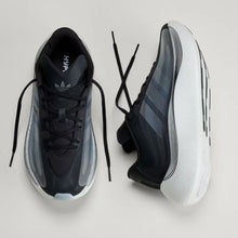 A pair of Adidas Huarache running shoes in black and gray with a white sole, shown from the front and side angles on a light gray background.