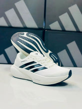 A pair of White Black Adidas Supernova Rise 3  in white and black, with one shoe standing upright and the other tilted on its side to show the sole tread. The Adidas branding and three-stripes logo are clearly visible.