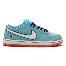 A Nike Dunk sneaker in light blue suede with a white Swoosh, black laces, and a white midsole with an orange outsole.