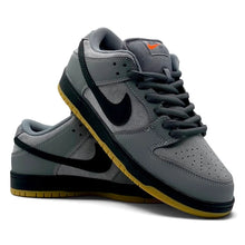 A pair of Nike Dunk Low sneakers in gray suede and leather, featuring a black Swoosh and a yellow gum outsole, set against a plain white background.