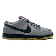 A Nike Dunk Low sneaker in gray suede and leather with a black Swoosh, black midsole, and a gum yellow outsole, shown from the side on a white background.