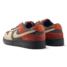 A pair of Nike Dunk Low sneakers in a muted colorway featuring rust red suede overlays, dark brown suede panels, beige leather overlays, and black rubber soles. The Nike branding is visible on the heel tabs.