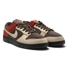 A pair of Nike Dunk Low sneakers in a brown, beige, and rust-orange colorway, featuring dark brown suede overlays, beige leather panels, and a black sole on a white background.