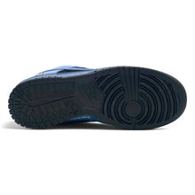 A close-up bottom view of a sneaker showing the dark textured rubber outsole and a blue collar detail against a white background.